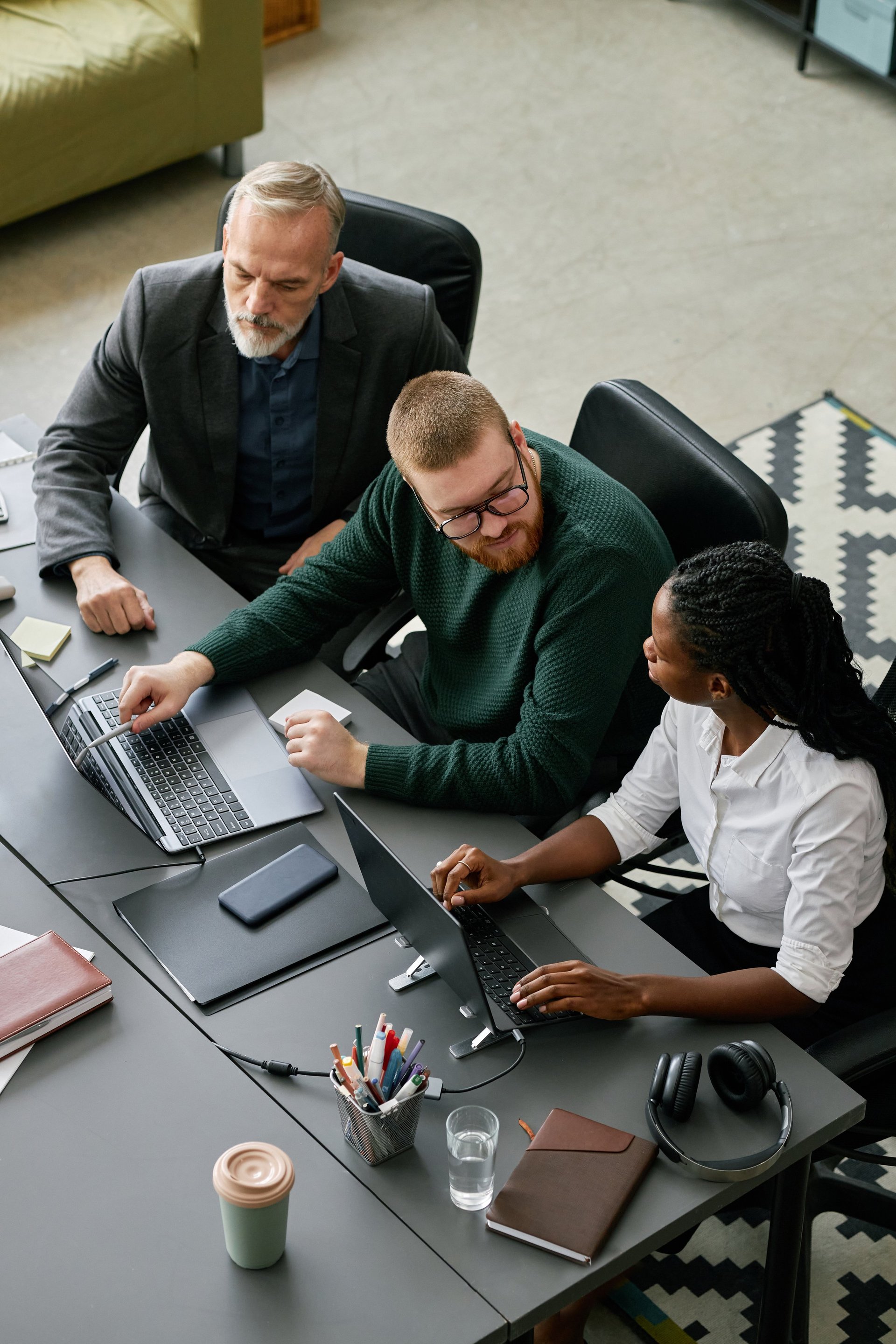Group of business professionals discussing project strategy around a conference table, with a man pointing at a laptop screen
