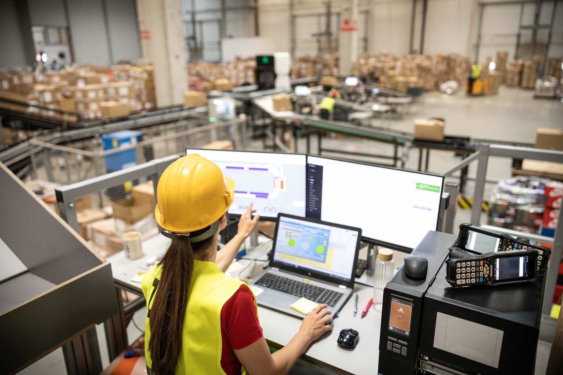 A woman analyzing real-time data on her computer within a warehouse, demonstrating tech integration in logistics