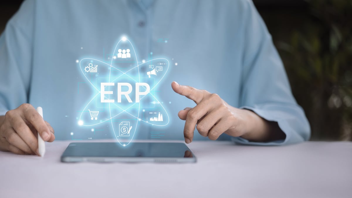 Businessman using tablet with ERP system hologram, concept of enterprise resource planning, business management, finance, supply chain, technology solution, and digital transformation.