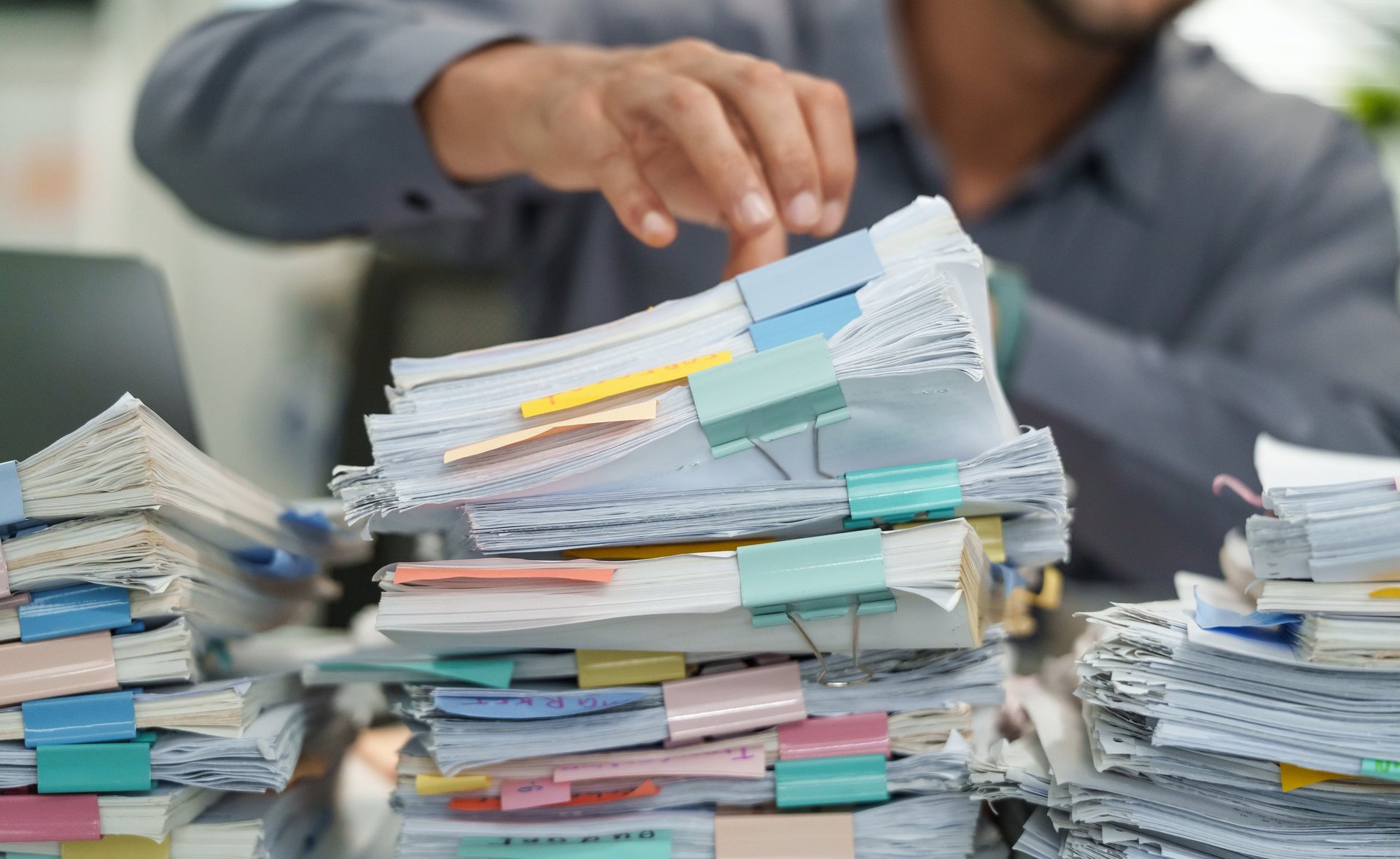 Close up of an office employee searching and arranging documents, files and paperwork on a desk
