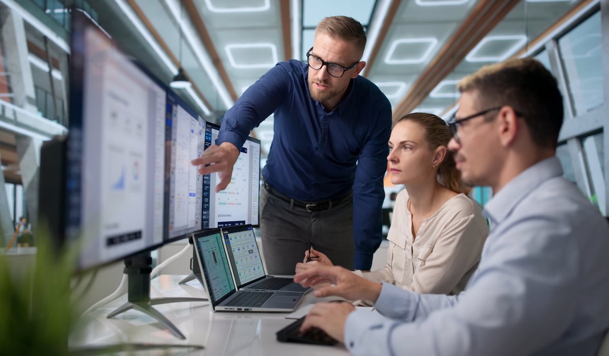 Project manager guides a diverse team using software for document control, representing a collaborative AI chatbot and conversational AI project team