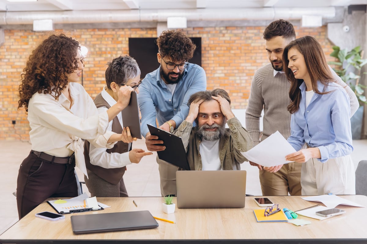 Colleagues surrounding a manager with documents and tablets, illustrating project status scattered across people, files and systems