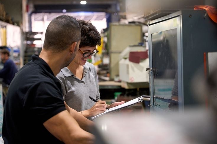 Two people in a lab reviewing a document together, with laboratory equipment visible in the background