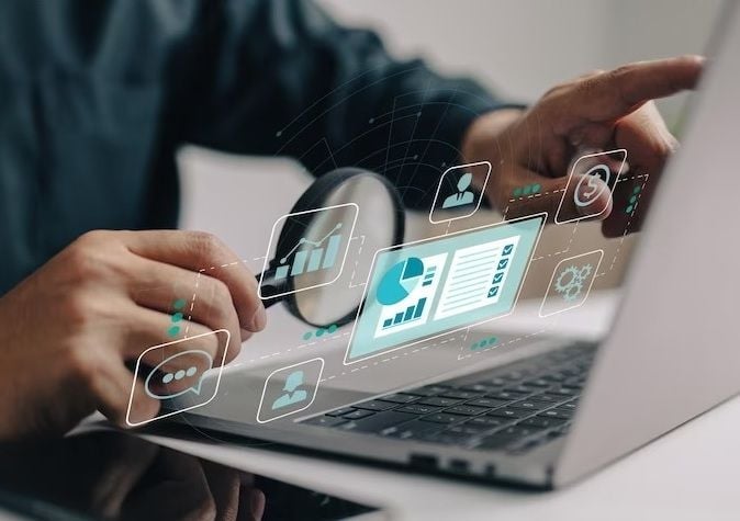 Person using laptop with floating digital icons and analytics displays representing business data and technology integration