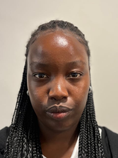 Portrait of a person with braided hair wearing a dark jacket against a neutral background