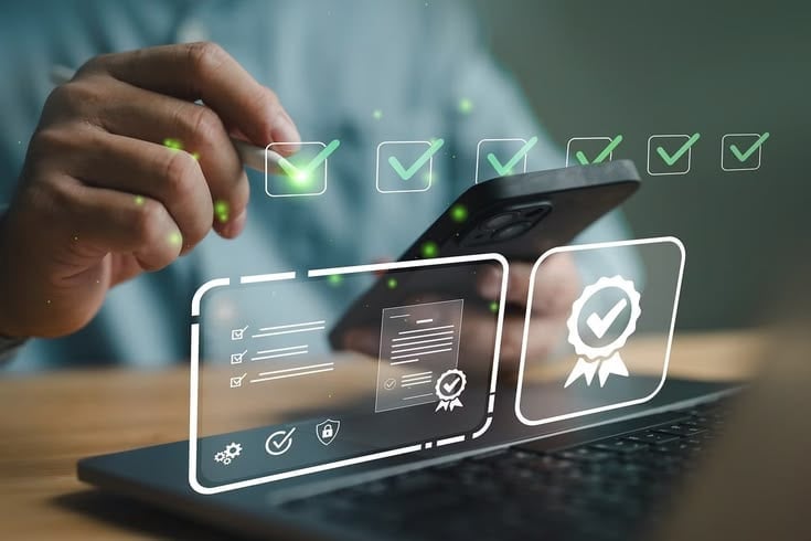 Hand touching digital checkmark icons floating above laptop and mobile device, representing task completion and quality assurance