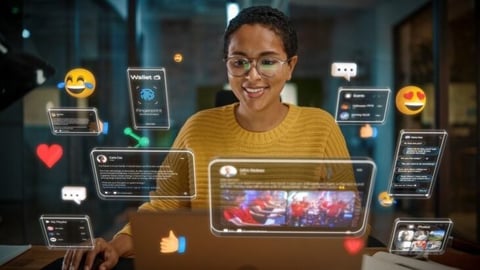 Woman wearing glasses and yellow sweater surrounded by floating digital interface screens and social media icons including hearts and emoji