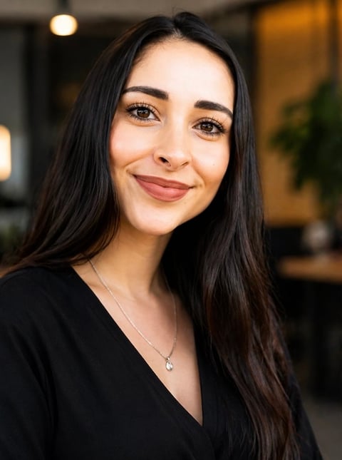 Portrait of a smiling woman with long dark hair wearing a black top against a blurred background